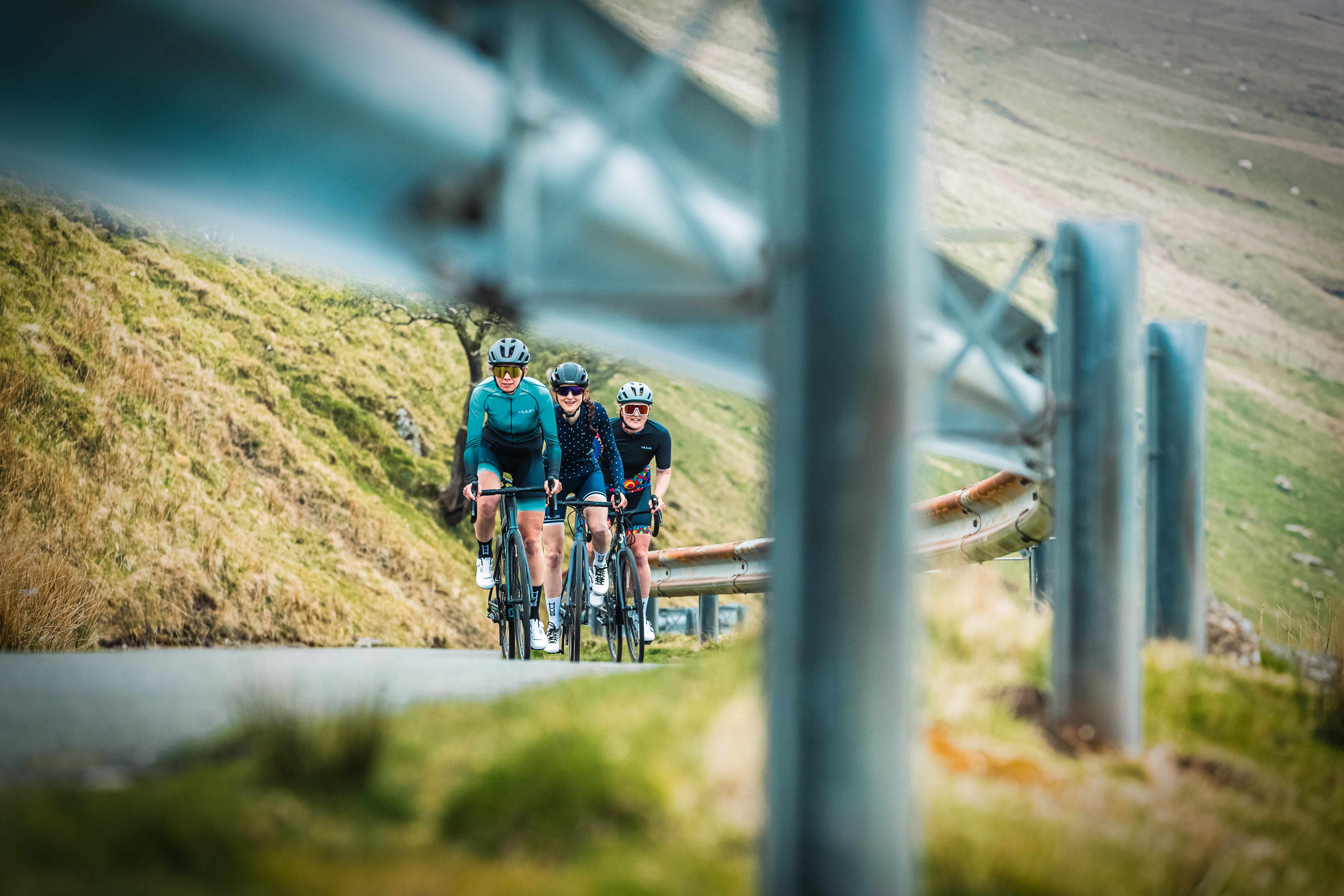 Three women riding road bikes on a rural climb